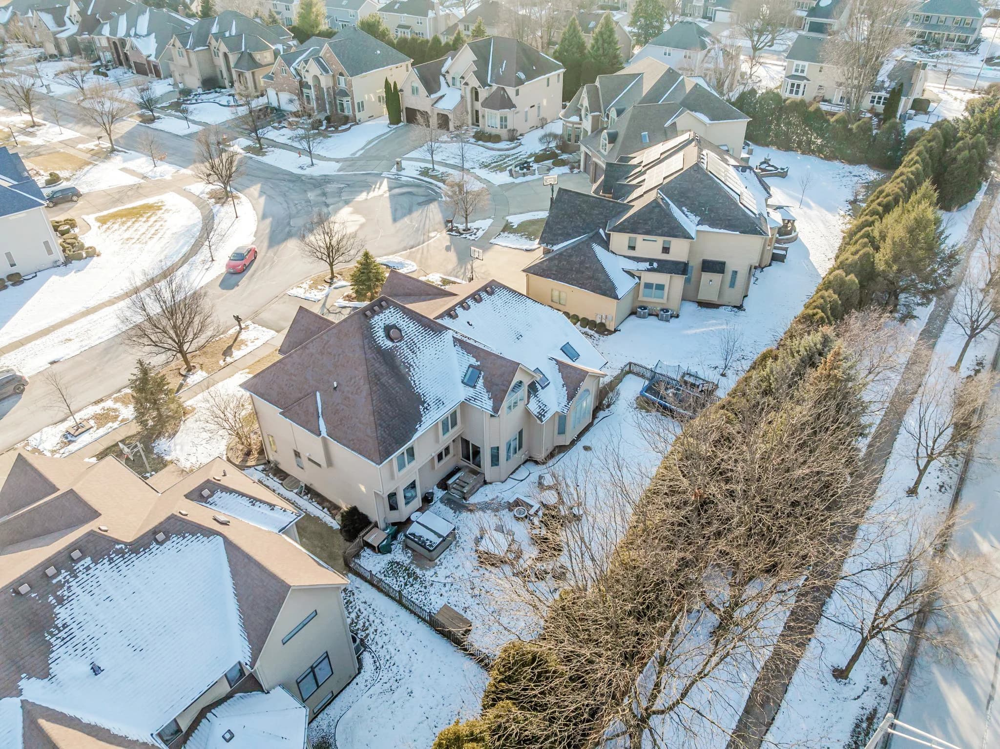 Before item removal & virtual cleaning: Aerial view of a residential property updated by removing snow and shifting the scene from winter to a greener season.