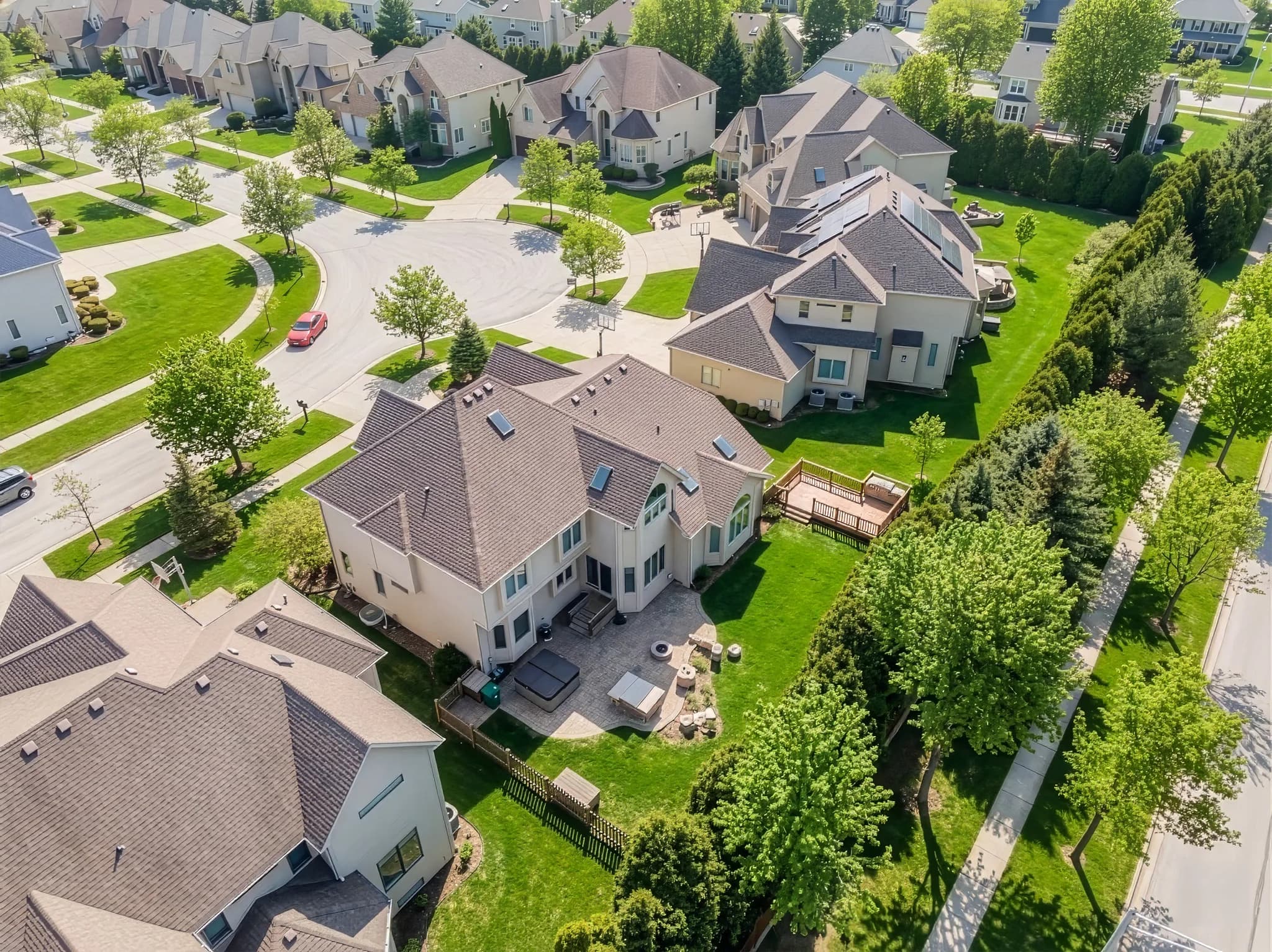 After item removal & virtual cleaning: Aerial view of a residential property updated by removing snow and shifting the scene from winter to a greener season.